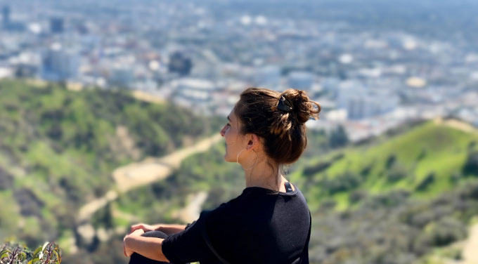 young woman sitting on mountain overlook