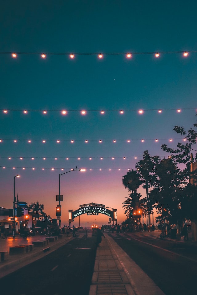 string lights over street and pier entrance at dusk