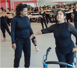 a dance instructor observes a student with a mobility aid